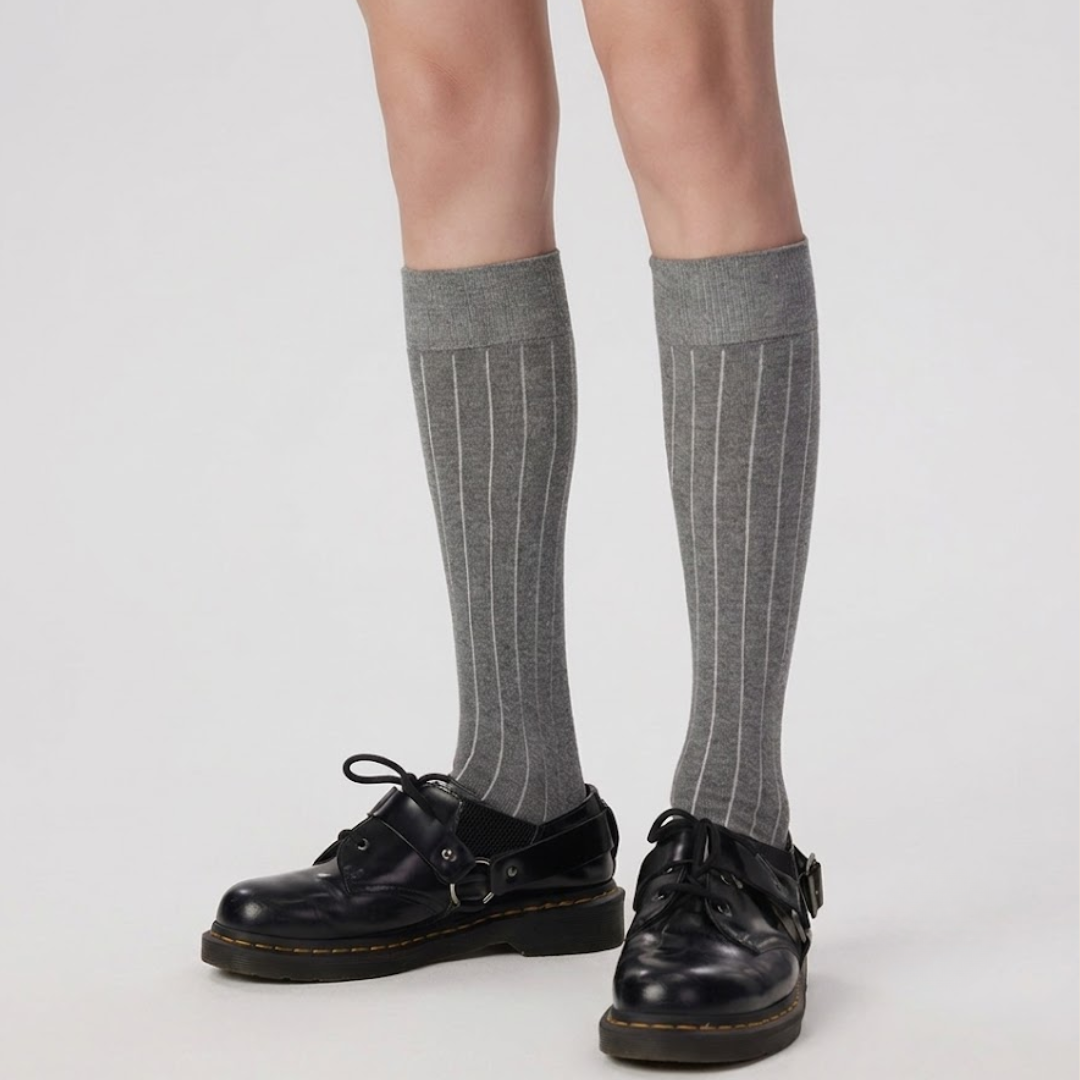 Men's high knee socks in grey ribbed knit, featuring a tall knee-high leg. Worn on legs with black shoes.