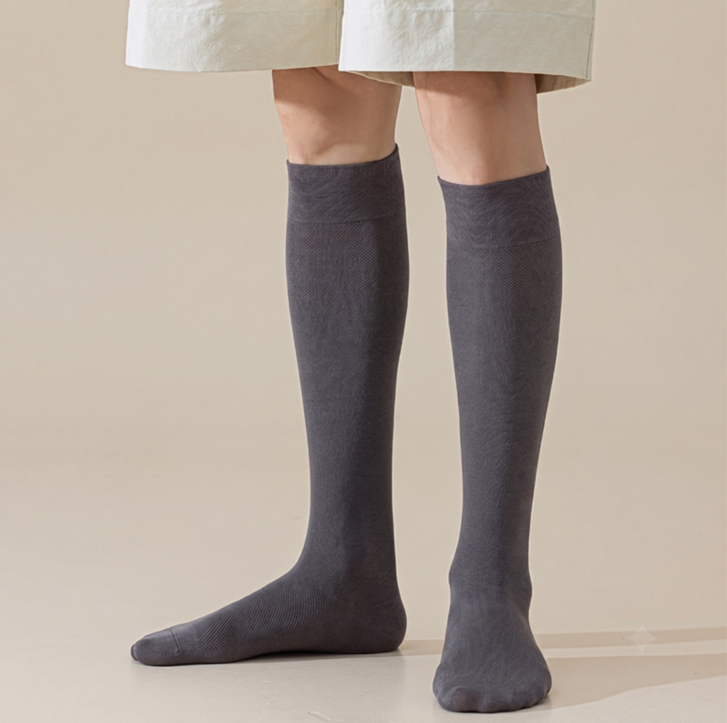 Men's knee socks in charcoal grey ribbed knit, featuring a tall leg. Worn on legs against a neutral backdrop.