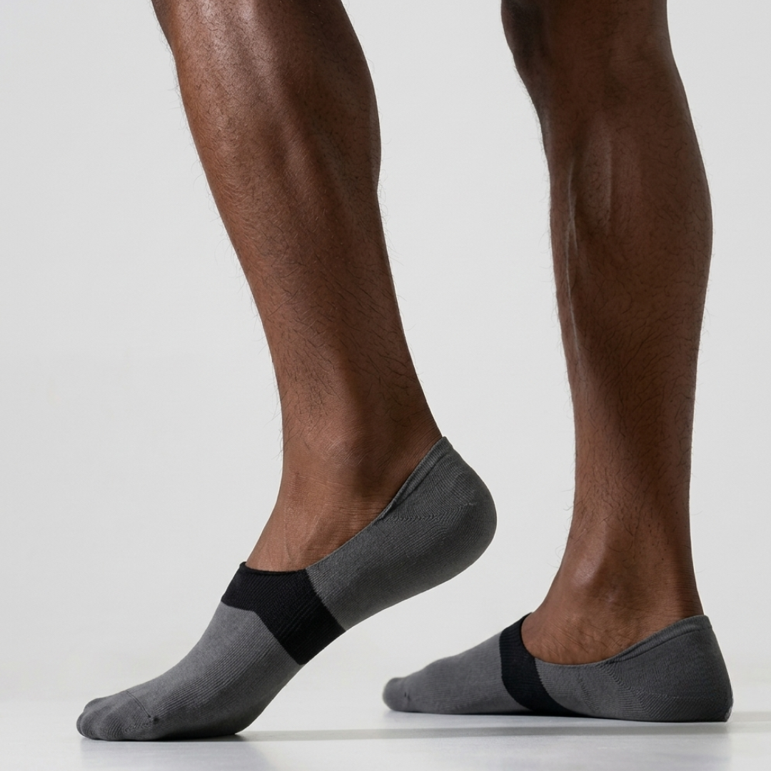 Men's loafer no show socks in grey with a black instep band, featuring an invisible low-cut design. Worn on feet to show the hidden fit.
