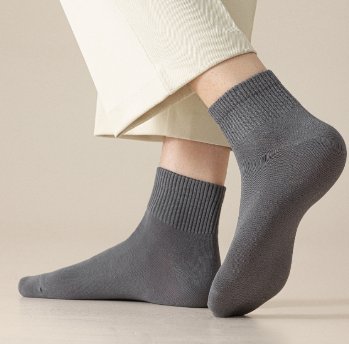 Men's quarter socks in grey, featuring a ribbed cushioned knit. Worn on feet with light trousers.