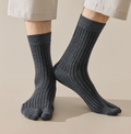 Men's tabi socks in charcoal grey, featuring a split-toe ribbed knit. Worn on feet with rolled trousers.