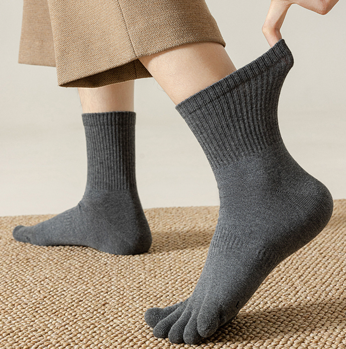 Men's toe socks in grey ribbed knit, featuring a crew length. Worn on the feet with trousers.