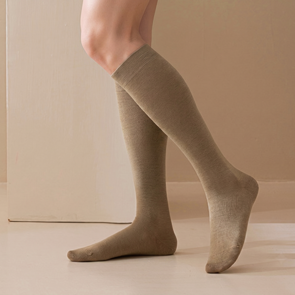 Merino knee socks in camel tan ribbed wool, featuring a soft knee-high leg. Worn on a leg against a warm backdrop.