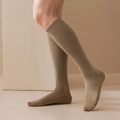 Merino knee socks in camel tan ribbed wool, featuring a soft knee-high leg. Worn on a leg against a warm backdrop.