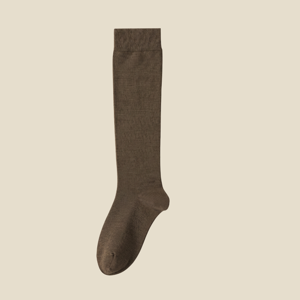 Merino knee socks in olive green ribbed wool, featuring a cozy leg. Worn on legs in a relaxed pose.