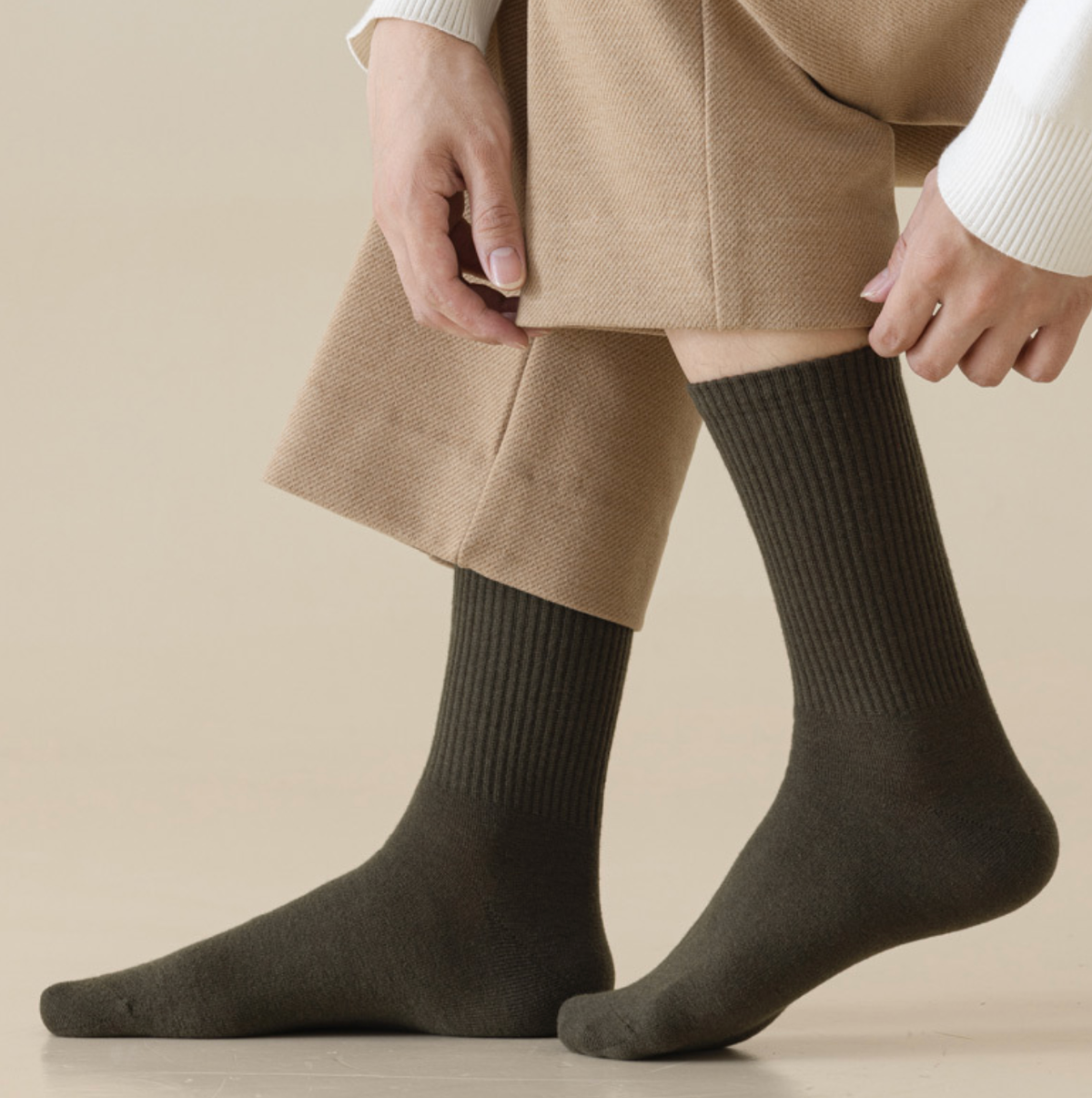 Men's merino wool dress socks in olive green ribbed wool, featuring a smooth leg. Worn with tan trousers.