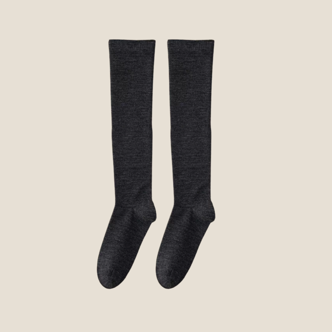 Merino wool knee socks in charcoal grey ribbed wool, featuring a smooth knee-high leg. Shown as an upright flat-lay pair on a neutral backdrop.