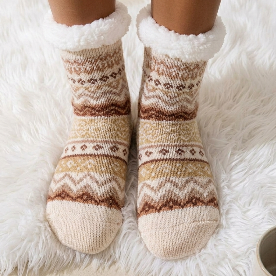 Non-skid slipper socks in orange Fair Isle knit, featuring an anti-slip gripped sole. Worn on feet on a fluffy rug.