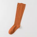 Orange knee high socks in warm orange ribbed knit, featuring a smooth knee-high leg. Shown as a single flat-lay on a neutral backdrop.