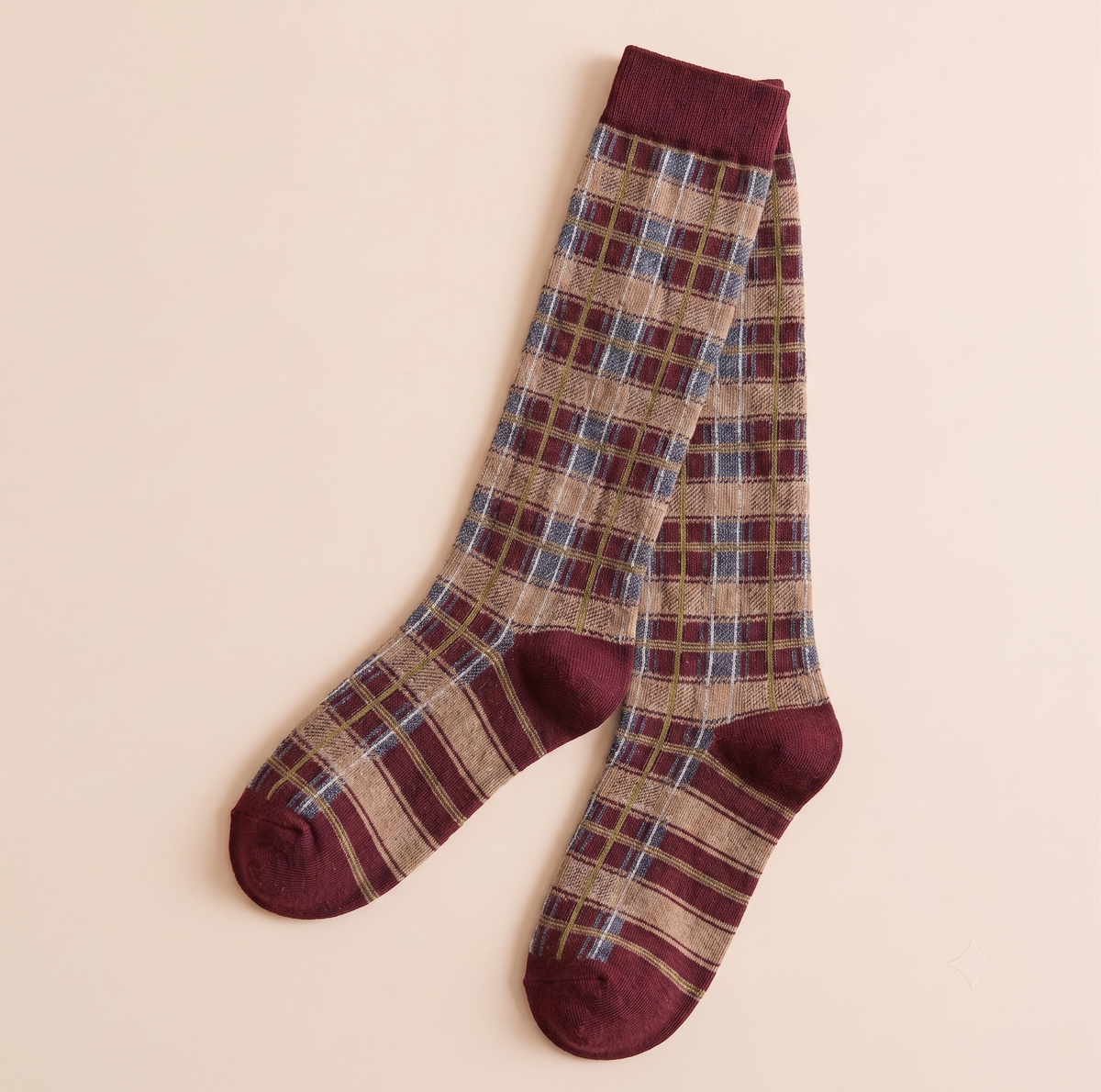 Over the calf boot socks in burgundy plaid, featuring a tartan check pattern. Displayed flat as a pair on a neutral backdrop.