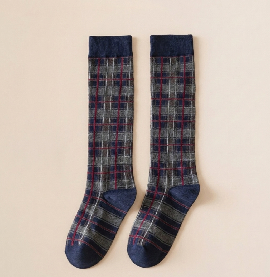 Over the calf boot socks in navy plaid, featuring a tartan check knit. Shown as a flat-lay pair on a light surface.