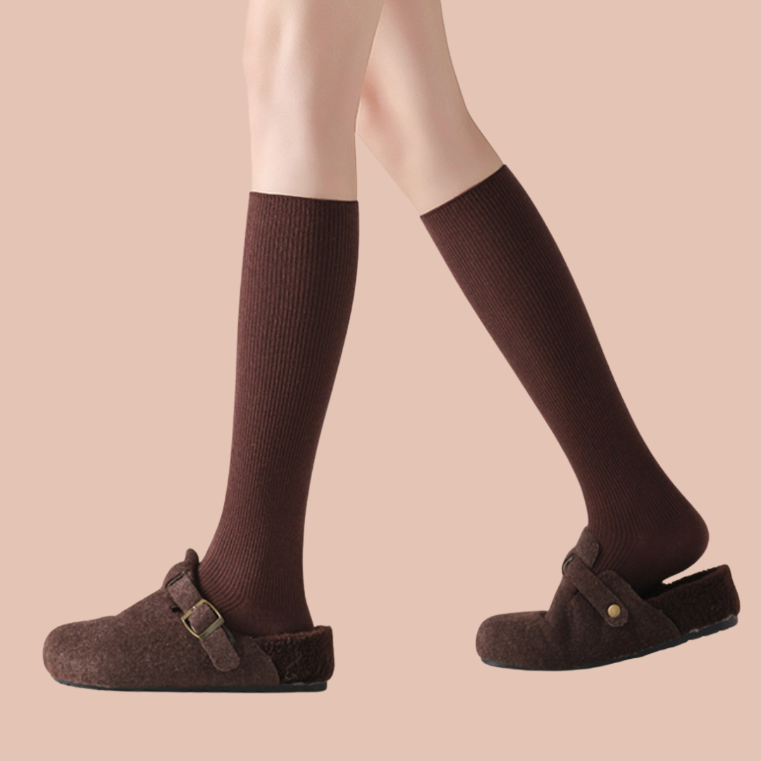 Over the calf wool dress socks in warm brown ribbed wool, featuring an over-the-calf length. Worn with brown mules.