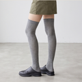 Over the knee socks for ladies in grey ribbed knit, featuring a thigh-high leg. Worn with black loafers and an olive skirt.
