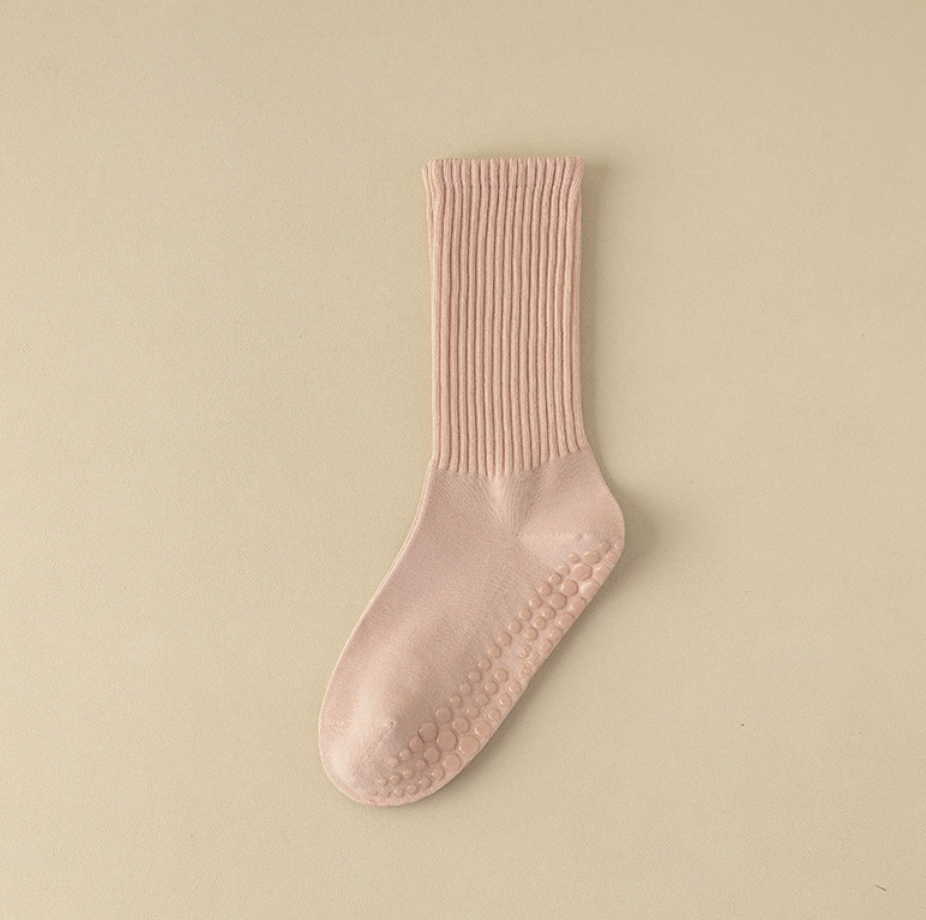 Pilates crew socks in blush pink ribbed knit, featuring grip dots on the sole. Shown as a single flat-lay.