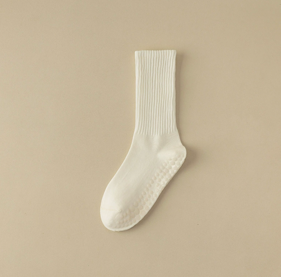 Pilates crew socks in cream ribbed knit, featuring a non-slip sole. Displayed flat on a neutral backdrop.
