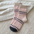 Pink fair isle socks in fuzzy pink Fair Isle knit, flat-lay pair on a knit blanket.