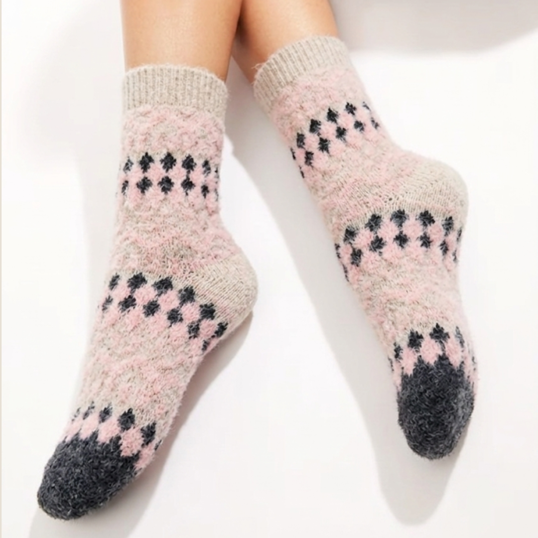 Pink fair isle socks in soft pink Fair Isle, worn on the feet, side view.