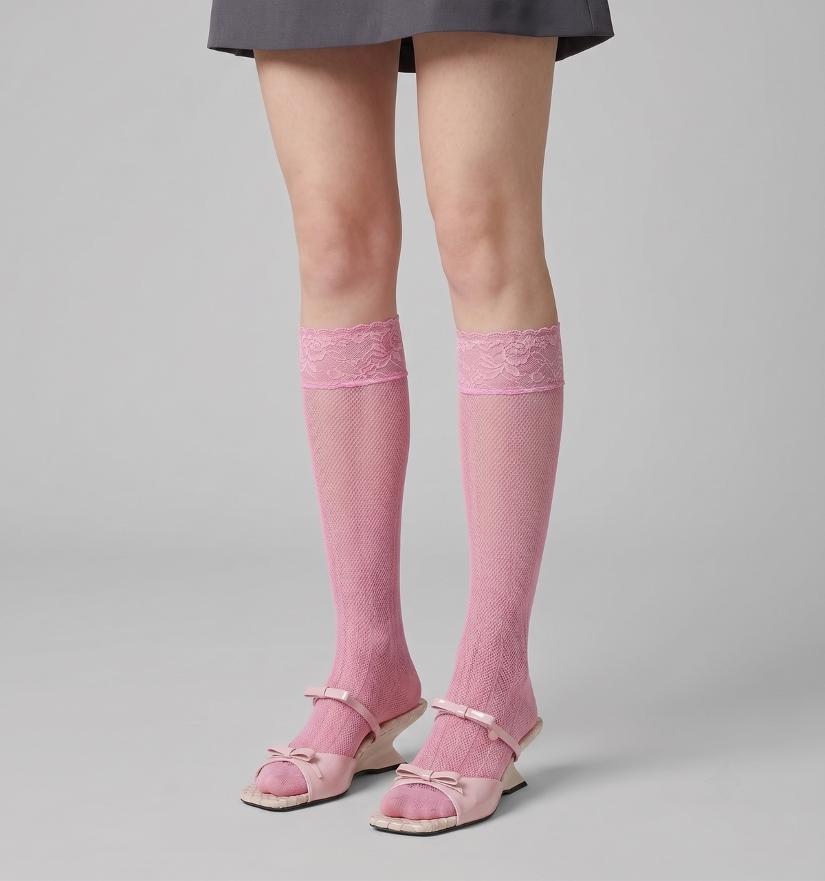 Pink knee socks in soft pink sheer knit, featuring a smooth leg. Styled with pink mary jane flats and a grey skirt.