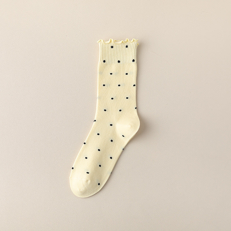 Pink ruffle socks shown in the yellow colorway with a polka-dot pattern and ruffle cuff, single sock flat.