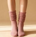 Pink slouch socks in dusty mauve knit, featuring a scrunched slouchy leg. Worn on the legs in a relaxed style.