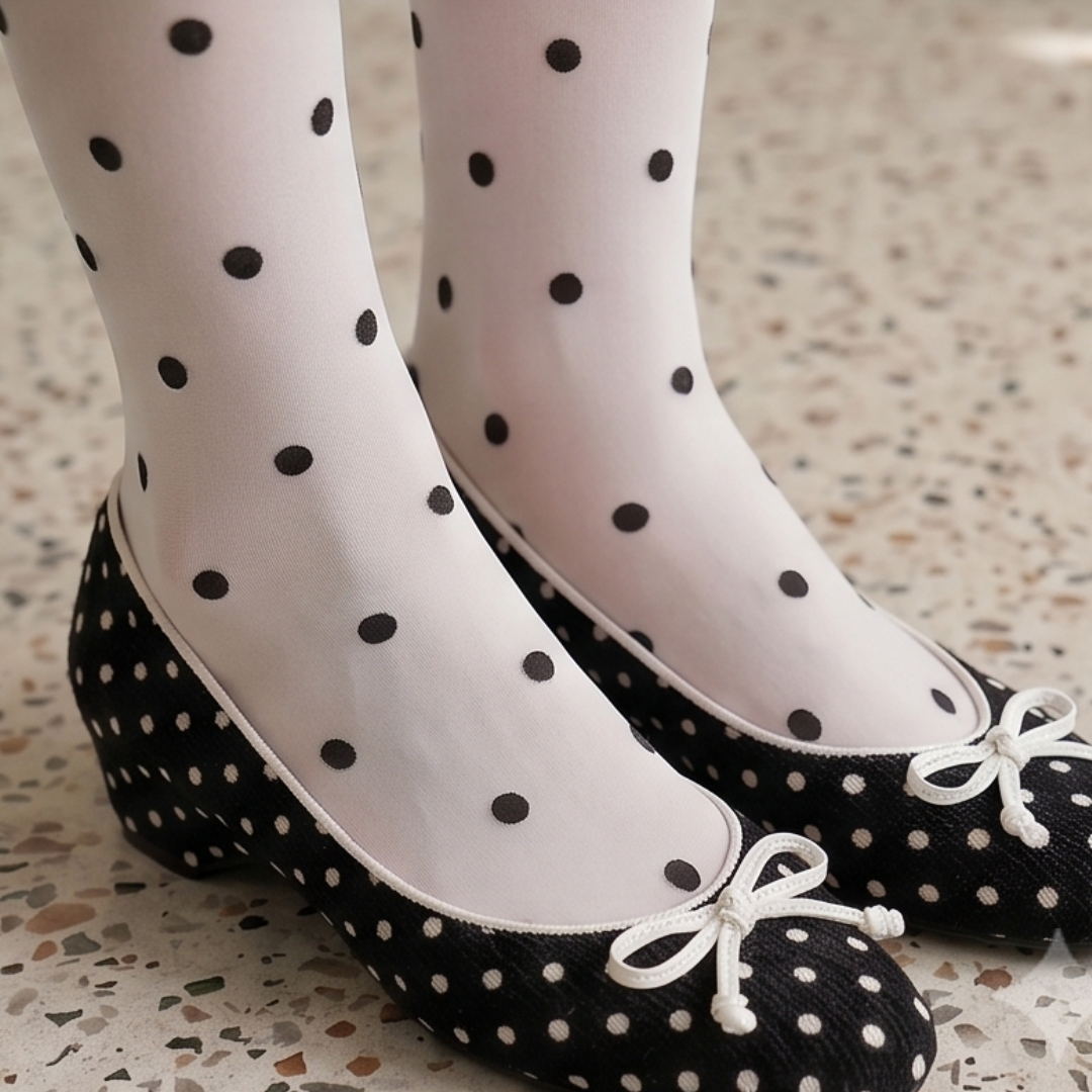 Polka dot knee socks in ivory sheer knit with black dots, featuring a delicate pattern. Styled with black bow ballet flats.