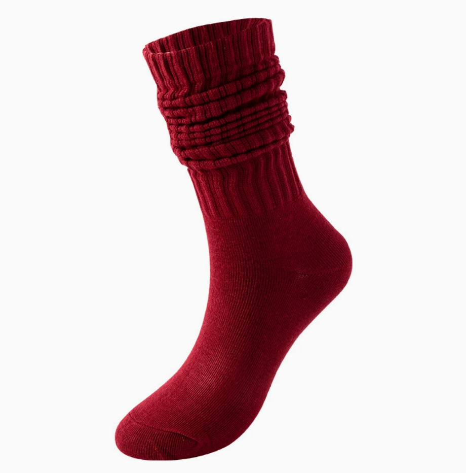 Red slouch socks in deep crimson knit, featuring a bunched slouchy leg. Worn on one foot in a relaxed style.