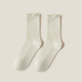 Ruffle crew socks in cream ribbed knit, featuring a frilled ruffle cuff. Shown as a flat-lay pair on a light surface.