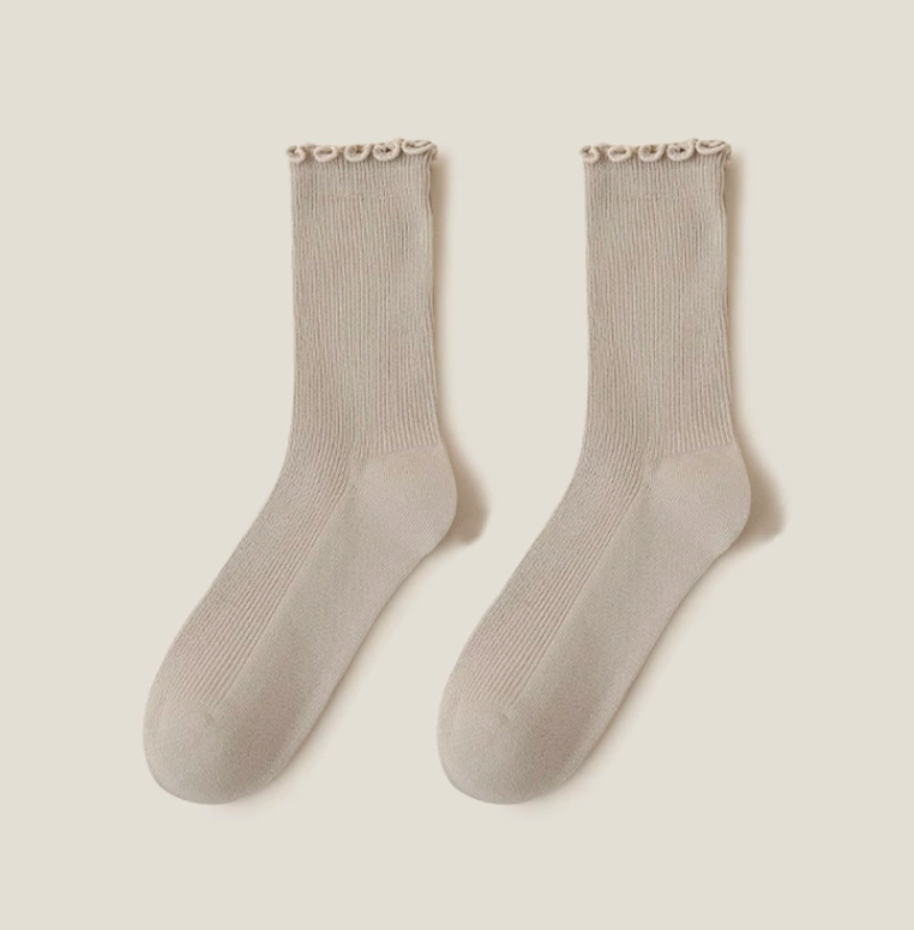 Ruffle crew socks in taupe ribbed knit, featuring a ruffle-trim cuff. Displayed flat as a pair on a neutral backdrop.