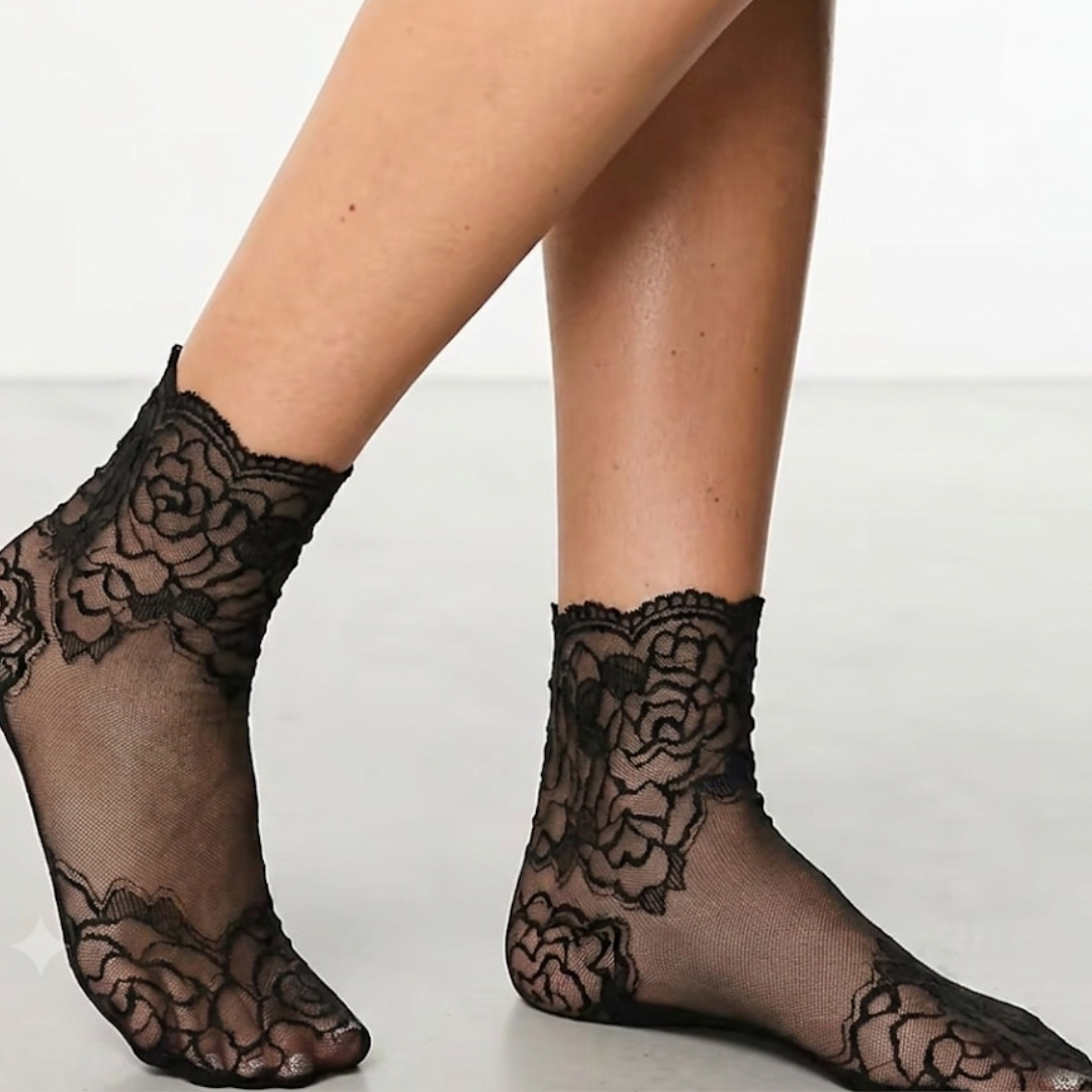 Sheer ankle socks in black floral lace, featuring a see-through mesh knit. Worn on feet in an elegant pose.