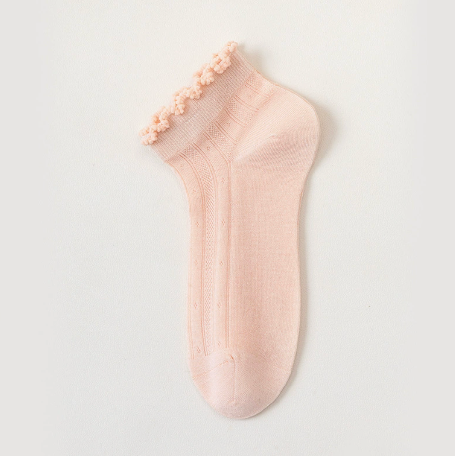 Sheer ankle socks in pink, featuring a delicate frill trim. Shown as a single flat-lay on a light backdrop.