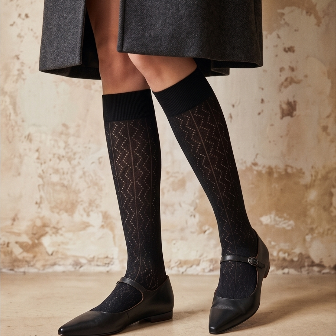 Sheer high knee socks in black textured mesh, featuring a subtle knit pattern. Worn with a grey skirt and ballet flats.