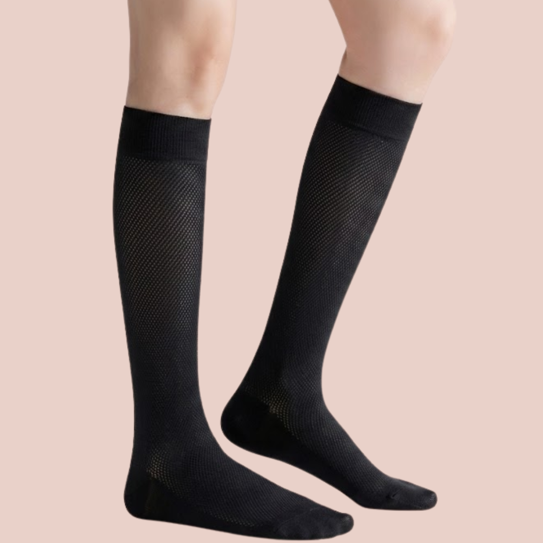 Sheer knee socks in black sheer knit, featuring a smooth lightweight leg. Shown as a flat-lay pair on a pink backdrop.