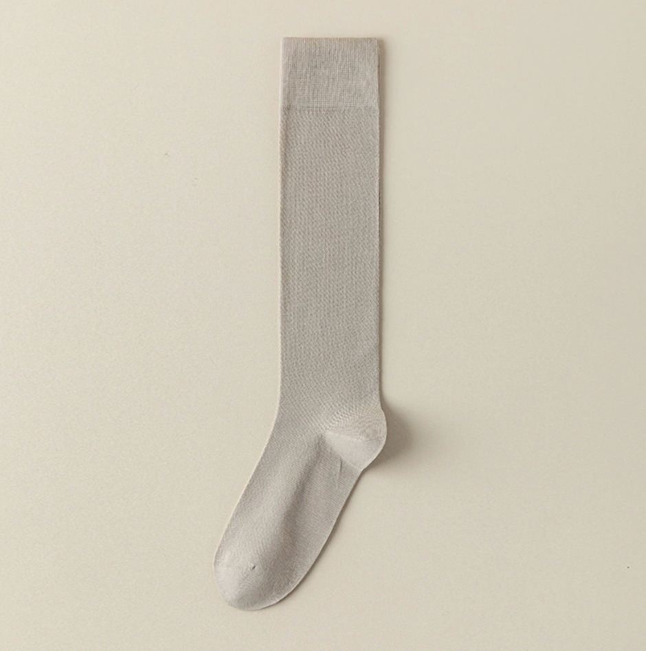 Sheer knee socks in cream mesh knit, featuring a fine ribbed texture. Shown as a single flat-lay on a neutral surface.
