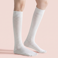 Sheer knee socks in white sheer knit, featuring a delicate mesh texture. Worn on legs against a pink backdrop.