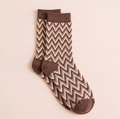Short boot socks in brown and cream, featuring a zigzag chevron knit. Shown as a flat-lay pair on a warm backdrop.
