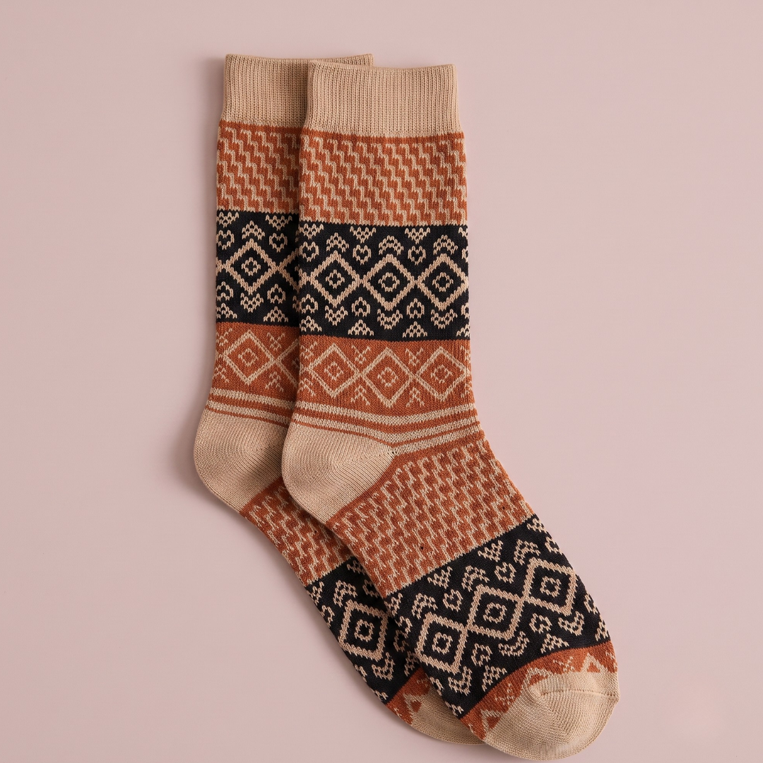 Short boot socks in rust, cream and black, featuring a Nordic Fair Isle pattern. Displayed flat as a pair on a light surface.