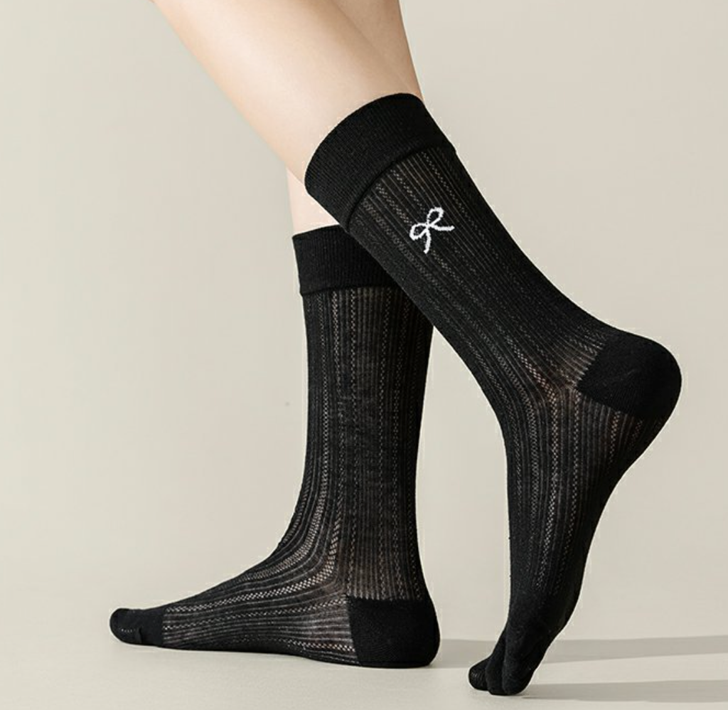 Split toe socks in black ribbed knit, featuring a split two-toe tabi construction. Worn standing to show the design.