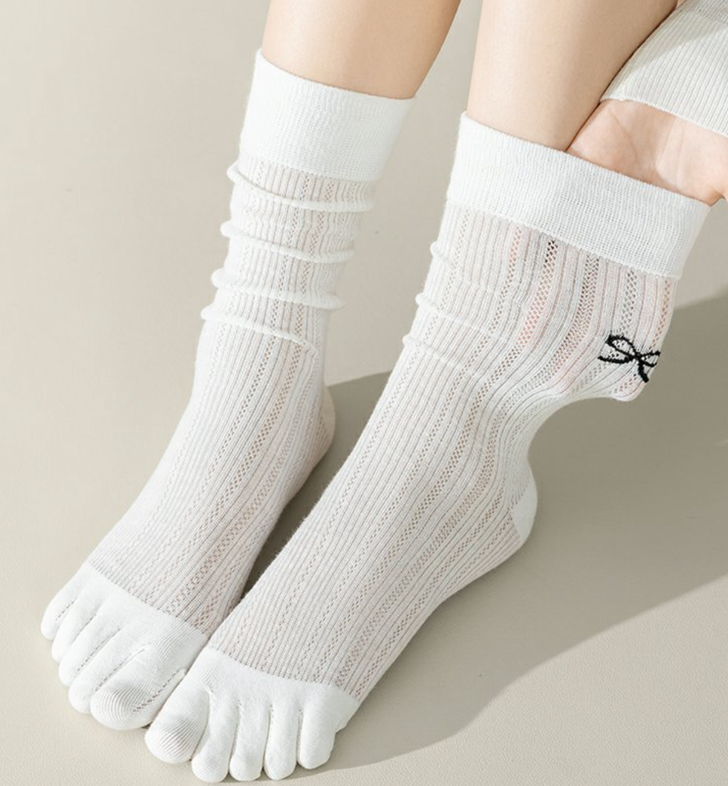Split toe socks in white ribbed knit, featuring a slouchy leg and two-toe tabi split. Worn on the feet.