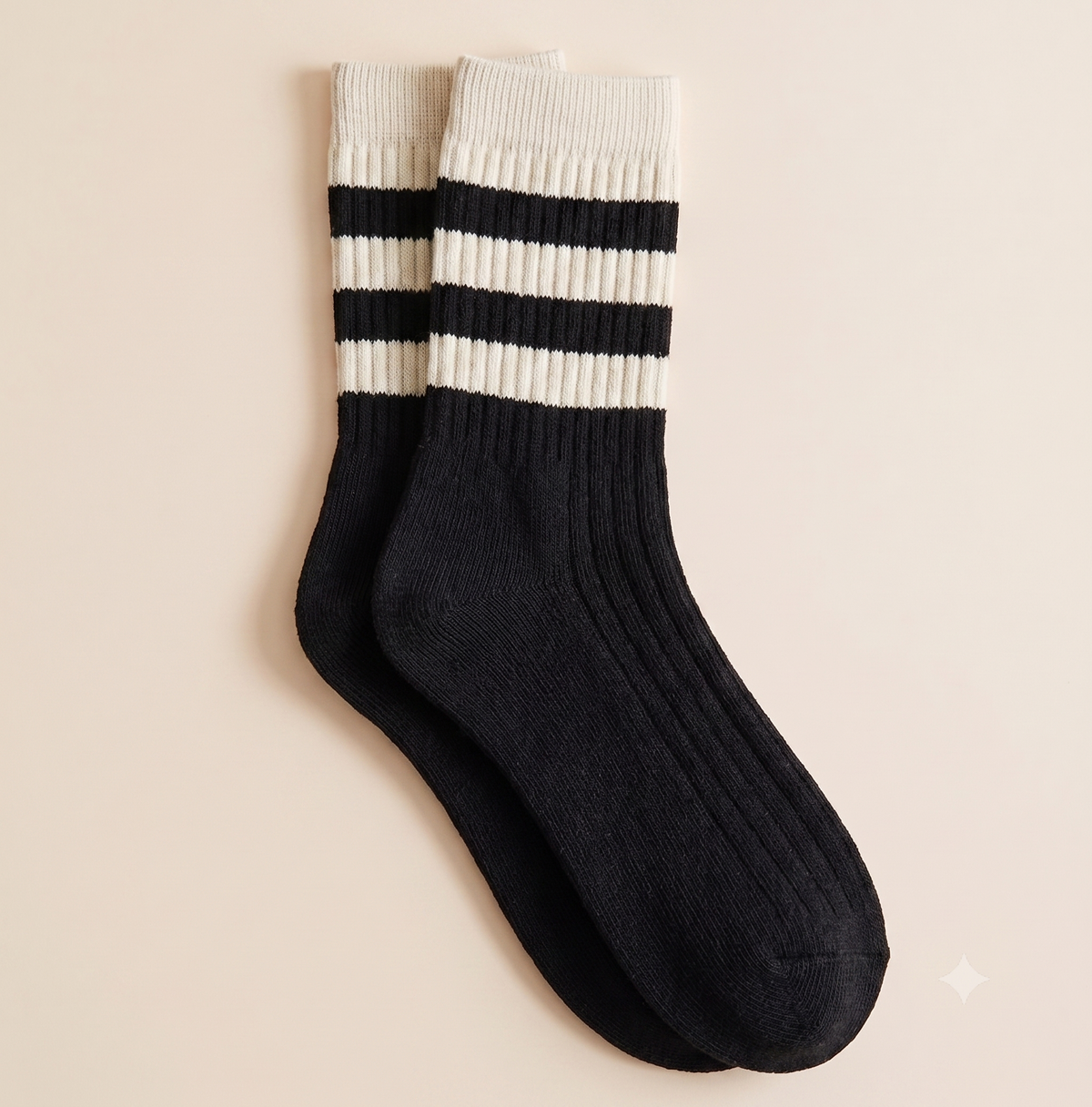 Striped crew socks in black ribbed knit, featuring cream varsity stripes at the cuff. Shown as a flat-lay pair on a cream backdrop.