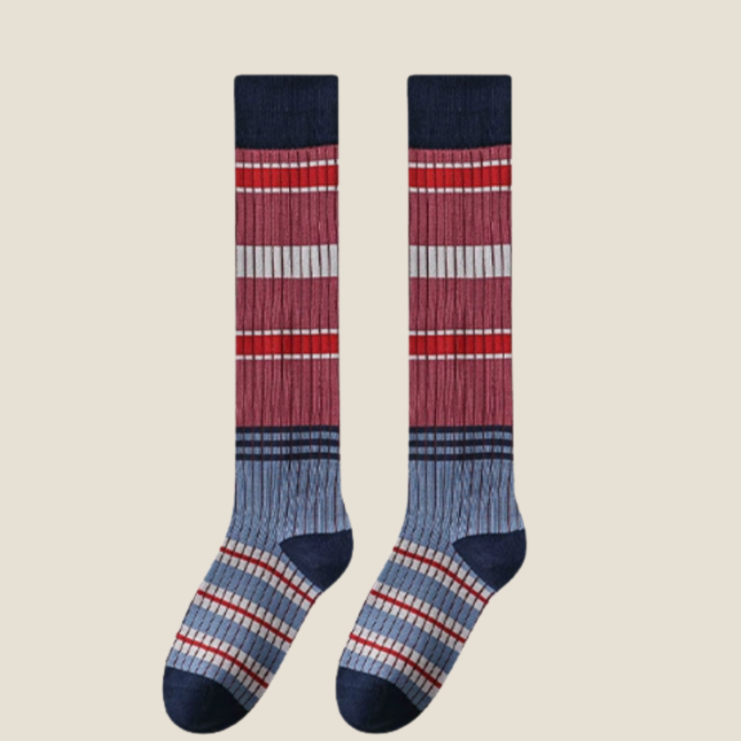 Striped high knee socks in red, blue and white stripes, featuring a bold ribbed knit. Shown as an upright flat-lay pair.