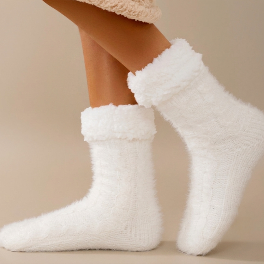 Thermal slipper socks in white fuzzy knit, featuring an extra-warm plush body. Worn on feet in a warm setting.