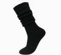Thick slouch socks in black knit, featuring a thick slouchy leg. Worn on one foot in a bunched style.