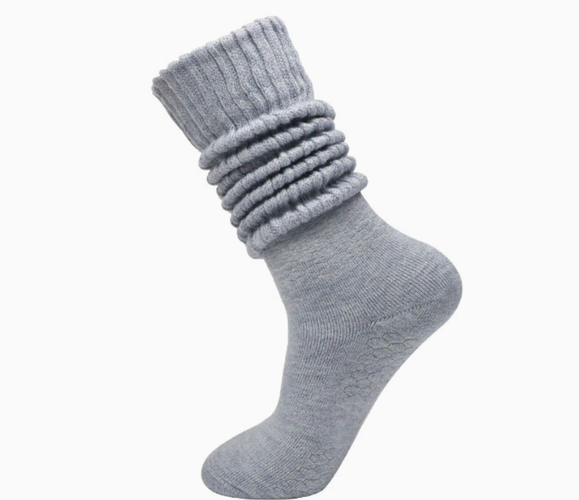 Thick slouch socks in light grey knit, featuring a chunky scrunched leg. Worn on one foot to show the plush texture.