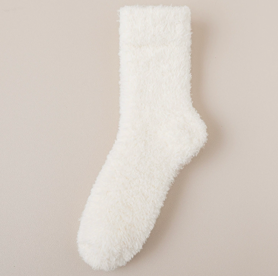 Thick socks for cold feet in ivory fuzzy knit, featuring a ribbed cuff. Shown flat on a warm neutral surface.