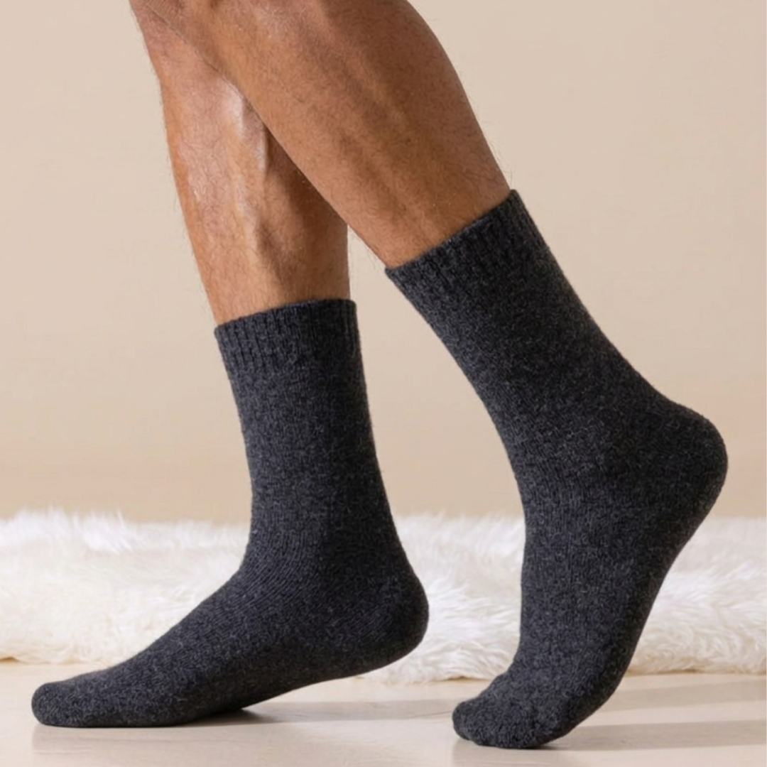 Thick socks for men in charcoal wool blend, featuring a warm ribbed knit. Worn on legs in a cozy setting.