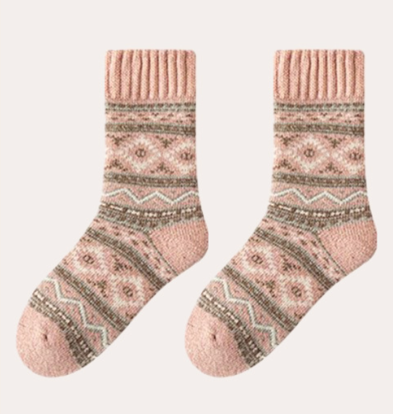 Thick socks for women in soft pink wool, featuring a cream Nordic snowflake pattern. Shown as a flat-lay pair on a light surface.