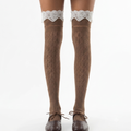 Thigh high cute lace stockings in brown pointelle knit with a white lace top, worn on the legs with brown shoes.
