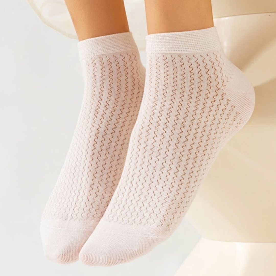 Thin ankle socks in white, featuring a delicate pointelle knit. Worn on feet in a soft studio setting.