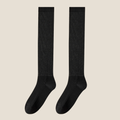 Thin socks for loafers in black lightweight ribbed knit, a flat-lay pair on a beige background.