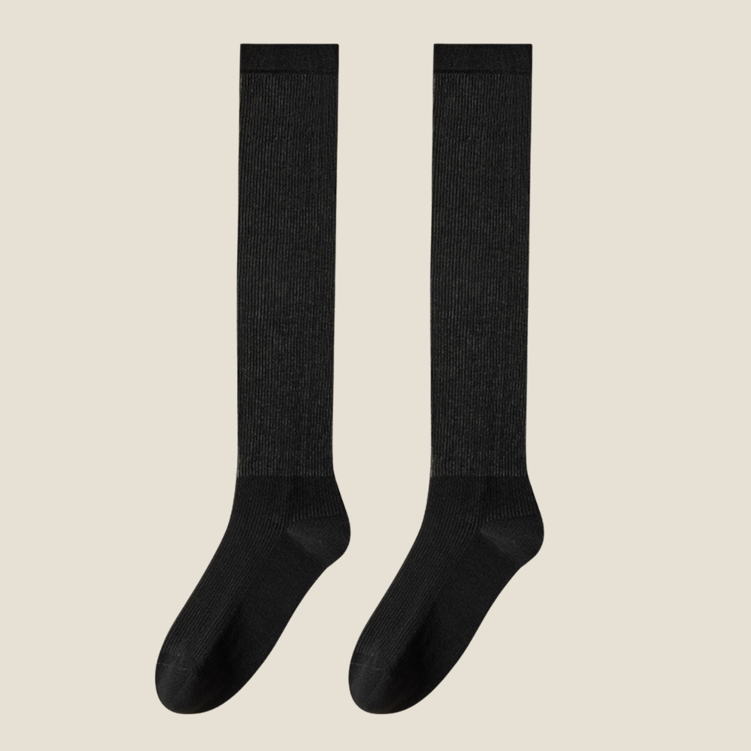 Thin socks for loafers in black lightweight ribbed knit, a flat-lay pair on a beige background.